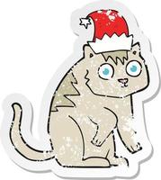 retro distressed sticker of a cartoon cat wearing christmas hat vector