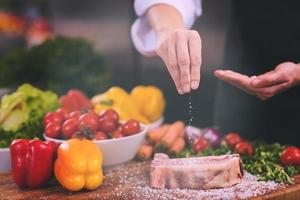 Chef putting salt on juicy slice of raw steak photo