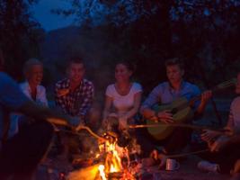 young friends relaxing around campfire photo