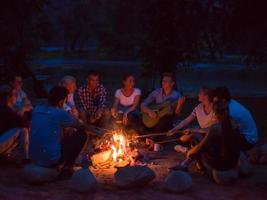 young friends relaxing around campfire photo