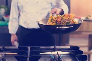 chef flipping vegetables in wok photo