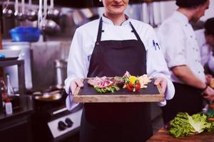 female Chef holding beef steak plate photo