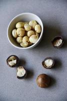 Delicious peeled Macadamia nut in a salad bowl on a gray background. The kernels of a delicious Macadamia nut close-up. photo