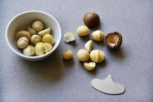 deliciosa nuez de macadamia pelada en una ensaladera sobre un fondo gris. los granos de un delicioso primer plano de nuez de macadamia. foto