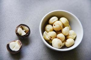 Delicious peeled Macadamia nut in a salad bowl on a gray background. The kernels of a delicious Macadamia nut close-up. photo