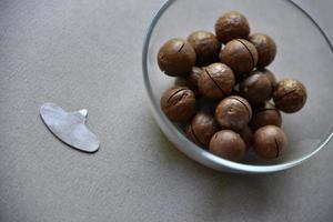 Macadamia nut in a dish with a bottle opener on a gray background. Macadamia nut prepared for use in a vase. Delicious breakfast of nuts. photo
