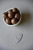 Macadamia nut in a dish with a bottle opener on a gray background. Macadamia nut prepared for use in a vase. Delicious breakfast of nuts. photo