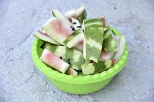 Watermelon rind and leftovers in a green basin. Vegetable garbage in the basket. Leftovers after meals. photo