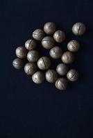 Not broken macadamia nuts on a black background in the group. photo