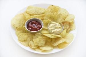 Fluted chips on a large plate with sauce and mayonnaise. Fast food fried potatoes with sauces. photo