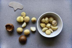 Delicious peeled Macadamia nut in a salad bowl on a gray background. The kernels of a delicious Macadamia nut close-up. photo