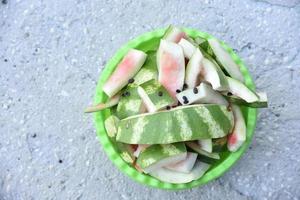 Watermelon rind and leftovers in a green basin. Vegetable garbage in the basket. Leftovers after meals. photo