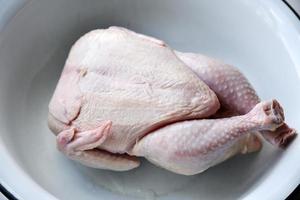 Raw chicken meat from the store. A chicken carcass in an iron basin. photo
