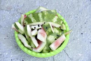 Watermelon rind and leftovers in a green basin. Vegetable garbage in the basket. Leftovers after meals. photo