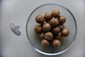 Macadamia nut in a dish with a bottle opener on a gray background. Macadamia nut prepared for use in a vase. Delicious breakfast of nuts. photo