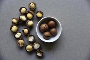Delicious macadamia nut in a cup on a gray background. Broken nuts and shells. photo