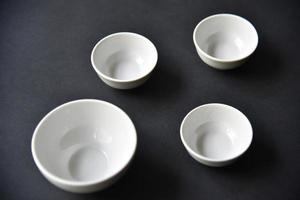 White porcelain salad bowls on a black background. Beautiful four white saucers on black. photo