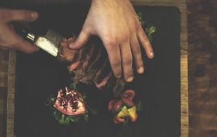 vista superior de las manos del chef sirviendo filete de ternera foto