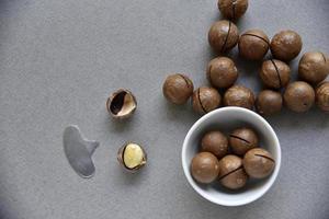 Macadamia nut in a dish with a bottle opener on a gray background. Macadamia nut prepared for use in a vase. Delicious breakfast of nuts. photo