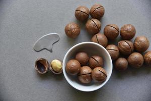 Macadamia nut in a dish with a bottle opener on a gray background. Macadamia nut prepared for use in a vase. Delicious breakfast of nuts. photo