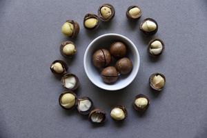Delicious macadamia nut in a cup on a gray background. Broken nuts and shells. photo