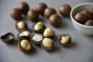 Delicious macadamia nut in a cup on a gray background. Broken nuts and shells. photo