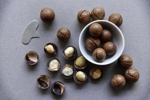 Macadamia nut in a dish with a bottle opener on a gray background. Macadamia nut prepared for use in a vase. Delicious breakfast of nuts. photo