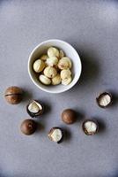 Delicious peeled Macadamia nut in a salad bowl on a gray background. The kernels of a delicious Macadamia nut close-up. photo