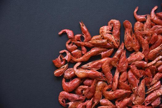 Lots of red delicious shrimp as background. Appetizer of dried peppered shrimp on a black background. The appetizer is salty with beer. photo