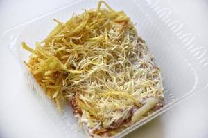 Meat salad with vegetables and cheese in a plastic container. Delicious breakfast on a white background. photo