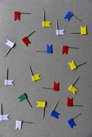 Multicolored iron paper clips on a gray background. Stationery paper fasteners scattered on a gray background like stars. photo