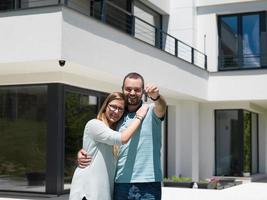 couple hugging in front of  new luxury home photo