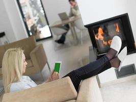 mujer joven que usa una tableta frente a la chimenea foto