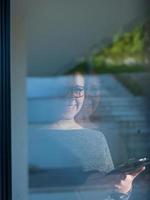 Woman using tablet at home by the window photo