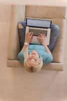 Young woman using laptop at home top view photo