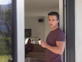 man drinking coffee in front of her luxury home villa photo