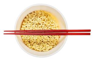 chopsticks over cup with dried instant noodles photo
