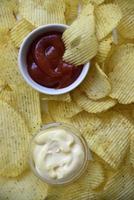 Yellow background of fried potatoes fast food. Fluted potato chips with sauce and mayonnaise. photo