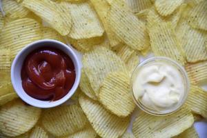 Yellow background of fried potatoes fast food. Fluted potato chips with sauce and mayonnaise. photo