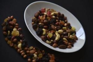 Assorted nuts on a white plate on a black background. A variety of delicious nuts on a plate. photo