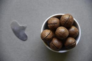 Macadamia nut in a dish with a bottle opener on a gray background. Macadamia nut prepared for use in a vase. Delicious breakfast of nuts. photo