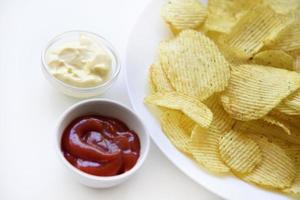 Fluted chips on a large plate with sauce and mayonnaise. Fast food fried potatoes with sauces. photo