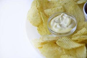 Fluted chips on a large plate with sauce and mayonnaise. Fast food fried potatoes with sauces. photo