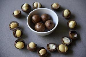 Delicious macadamia nut in a cup on a gray background. Broken nuts and shells. photo