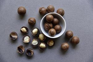 Macadamia nut in a dish with a bottle opener on a gray background. Macadamia nut prepared for use in a vase. Delicious breakfast of nuts. photo