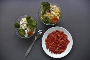A white plate with dried shrimp and salad in a bowl on a gray background. Red shrimp and salad as breakfast. photo