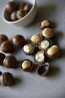 Delicious macadamia nut in a cup on a gray background. Broken nuts and shells. photo