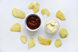 Corrugated potato chips with pepper on a white background. Delicious fast food chips. with sauce. photo