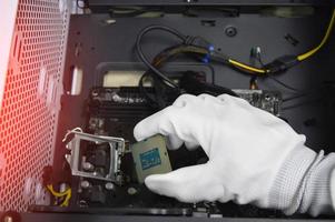 Image of a technician inserting a CPU chip onto a computer motherboard. photo