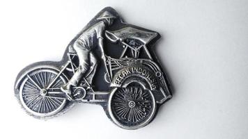 refrigerator magnet in the form of a rickshaw, pedicab is one of the means of transportation in Indonesia. fridge magnet isolated on a white background.high angle view. photo